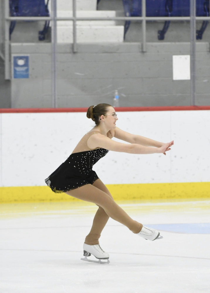 A figure skater is on one foot doing a spin with a smile on her face.